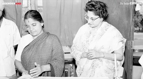 Durgabai Deshmukh standing at a table with papers beside another woman.